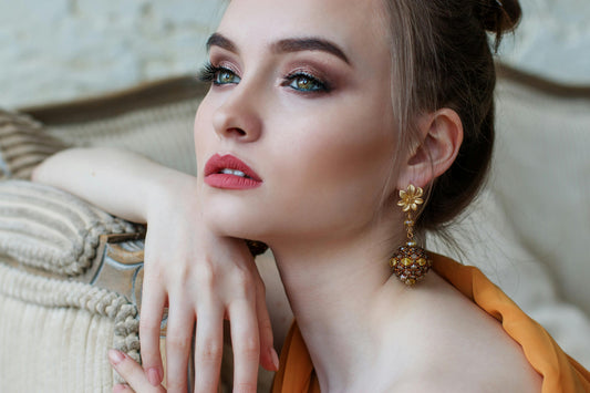 Femme portant des boucles d'oreilles fantaisie dorées assorties à une tenue élégante du quotidien.