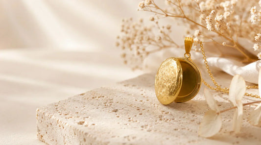Pendentif médaillon ouvrable personnalisé en acier inoxydable doré, posé sur une pierre naturelle dans une ambiance élégante et lumineuse.