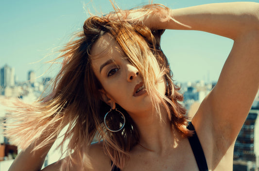 Femme portant de grandes boucles d'oreilles fantaisie pour transformer un look élégant.