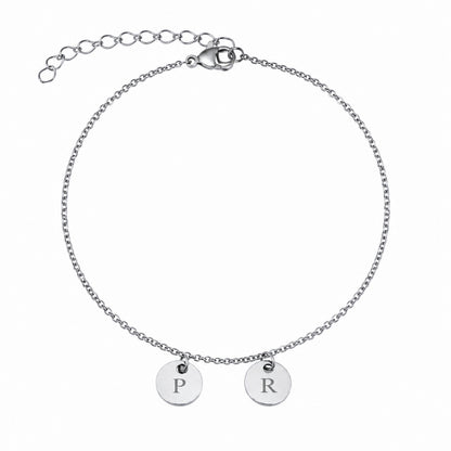 Bracelet chaîne personnalisé en acier argent avec deux médailles rondes gravées de lettres, fermoir réglable et finition brillante.