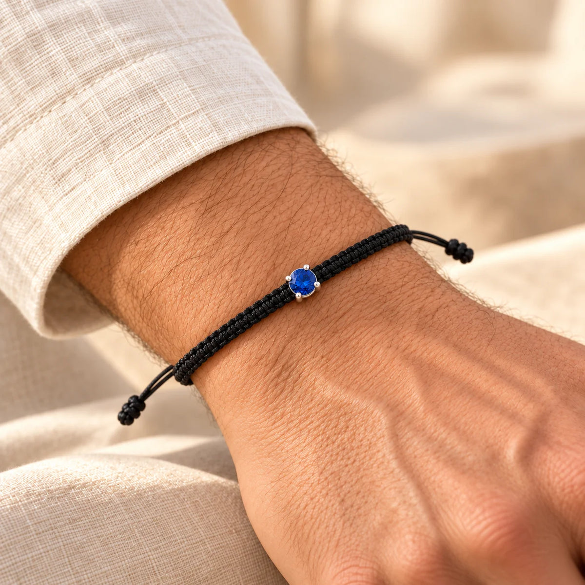 Bracelet cordon tressé noir ajustable serti d’un saphir de laboratoire, porté au poignet masculin