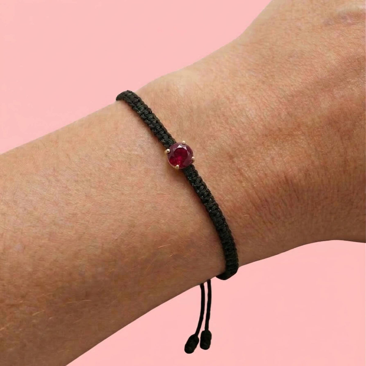 Bracelet cordon noir à rubis rouge de laboratoire serti d'or 750, porté au poignet
