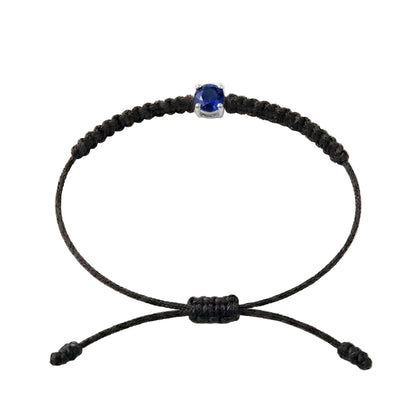 Bracelet cordon noir, pierre de saphir bleu de laboratoire sertie sur or 750/1000,
fermoir coulissant réglable