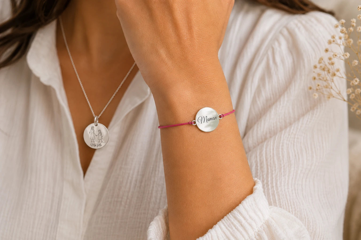 Femme portant un collier médaille argenté gravé « Ma fille » et un bracelet cordon rose personnalisé avec la gravure « Maman ».