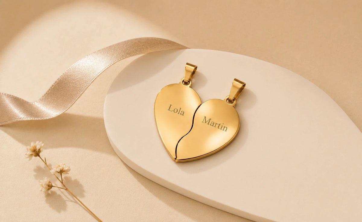 Pendentif cœur séparable doré personnalisé avec les prénoms Lola et Martin, présenté sur un support beige.