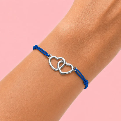 photo d'un poignet de femme qui porte un bracelet cordon bleu et coeurs entrecroisés en acier argenté 