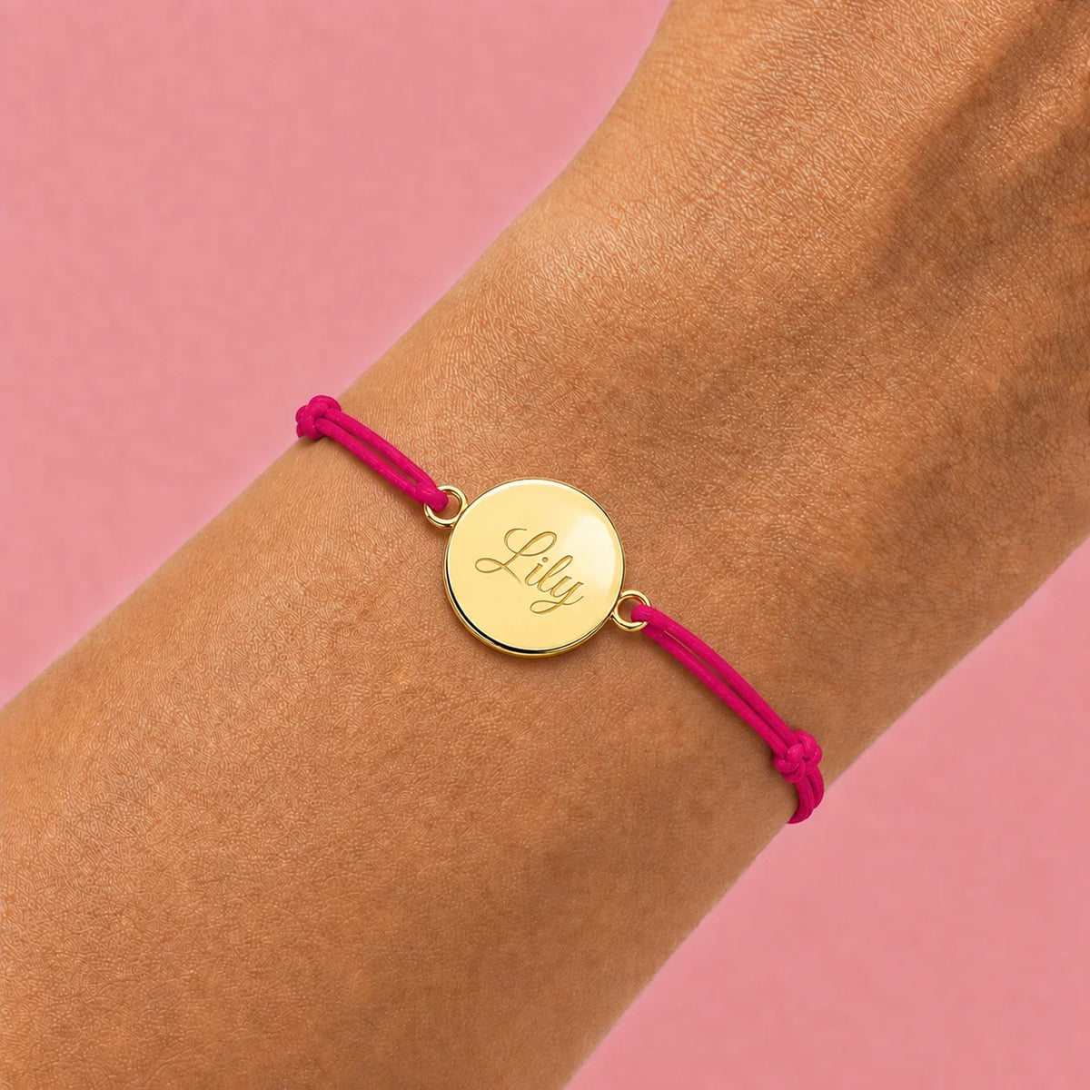 photo portée bracelet cordon mixte et ajustable personnalisé avec médaille dorée à graver et cordon rose framboise