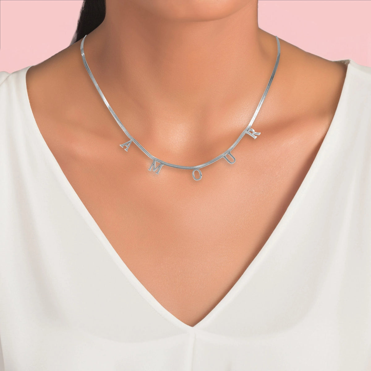 Collier argenté avec mot AMOUR porté sur un décolleté en V