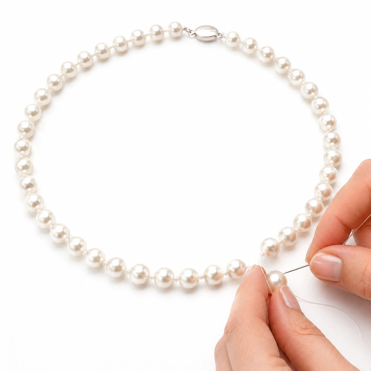 Renfilage à la main d’un collier de perles blanches en atelier – Les Inséparables